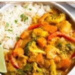 Large white bowl filled with Thai coconut chicken curry and white rice. It is garnished with a lime wedge and fresh cilantro.