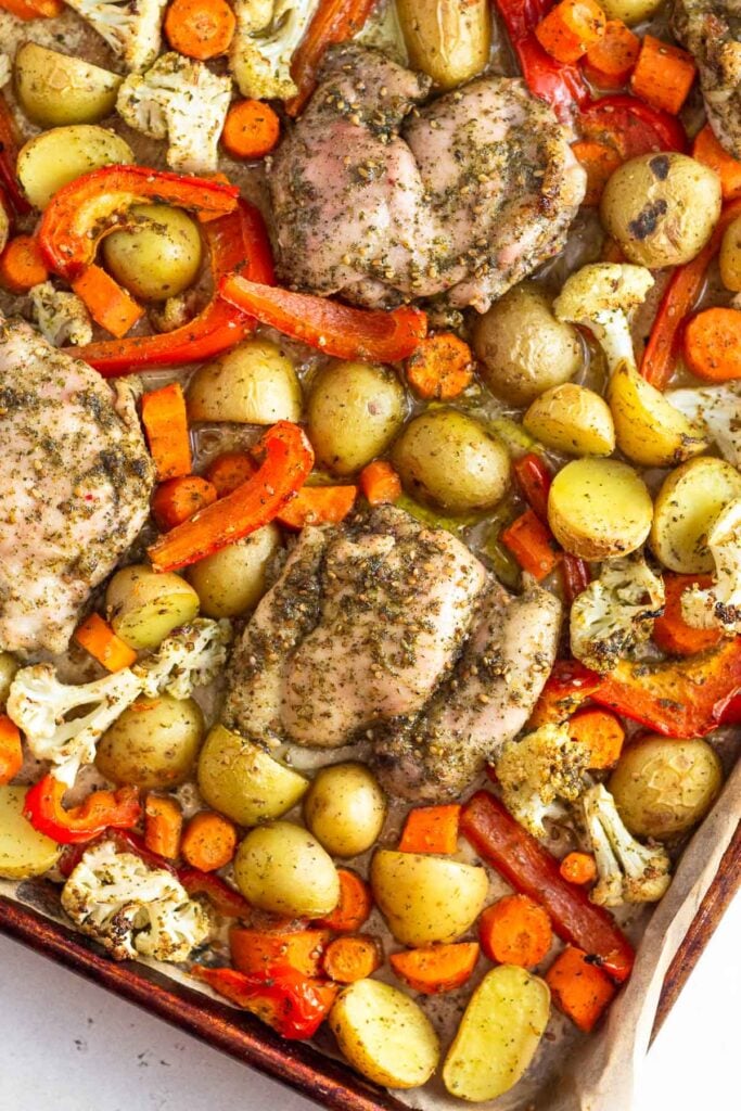 Sheet pan filled with roasted zaatar chicken and roasted potatoes, carrots, cauliflower, and peppers.