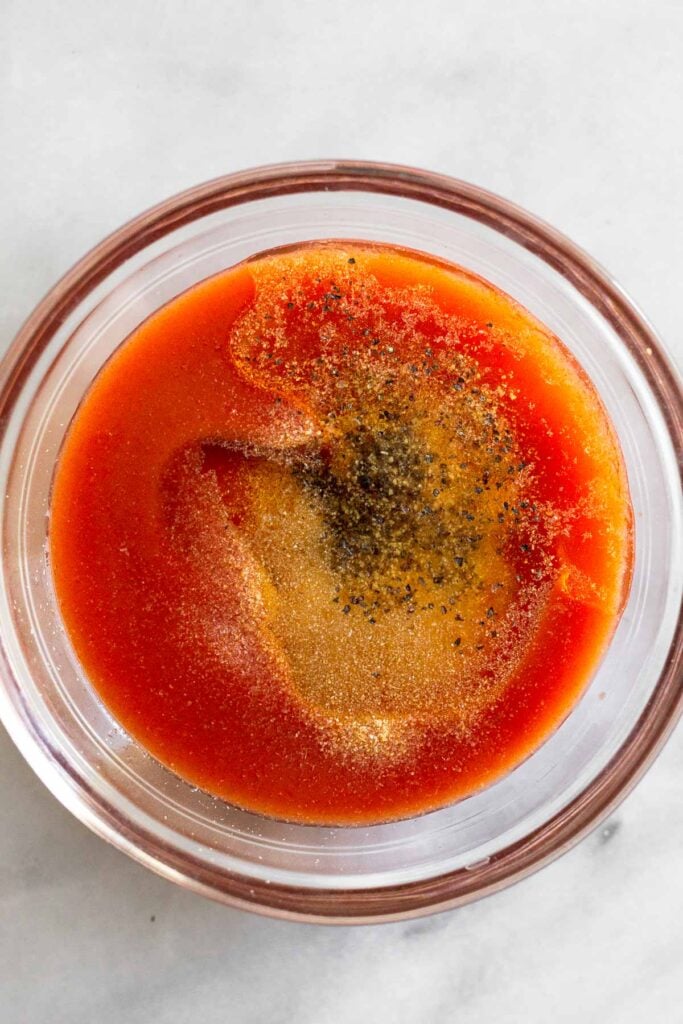 Small glass bowl with hot sauce, oil, and spices in it.