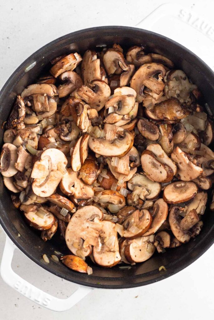 Dutch oven filled with sliced mushrooms.