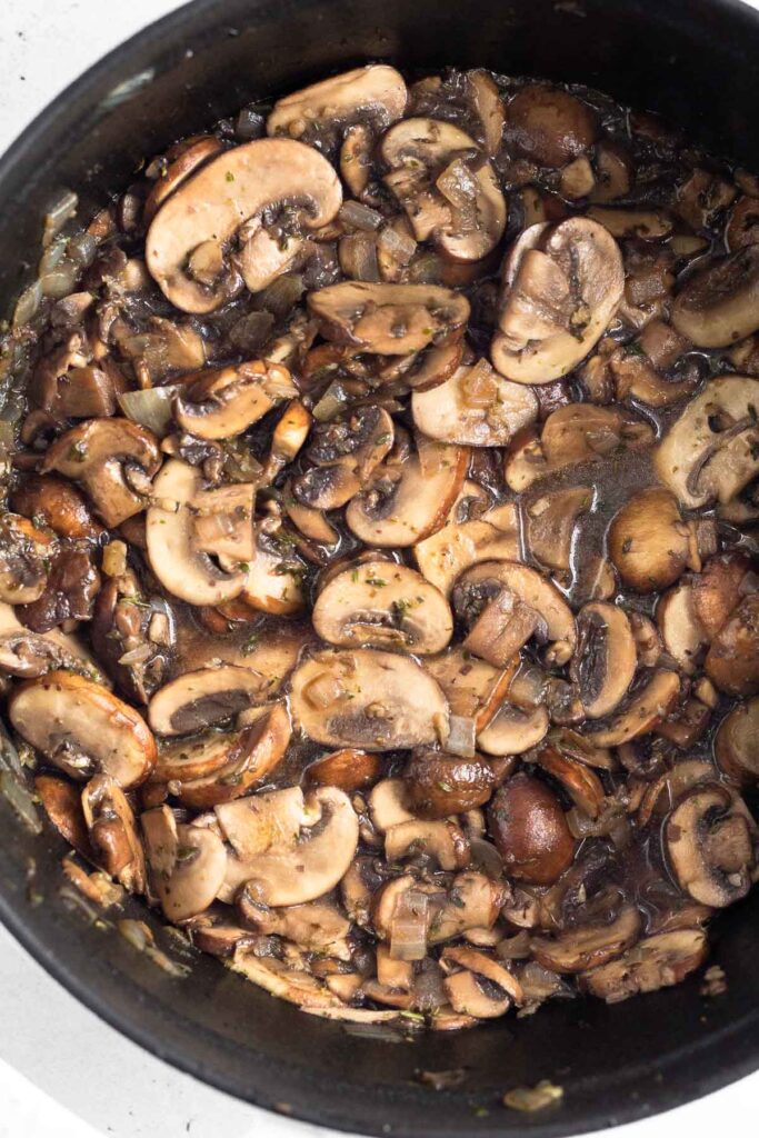Dutch oven filled with sautéed mushrooms.