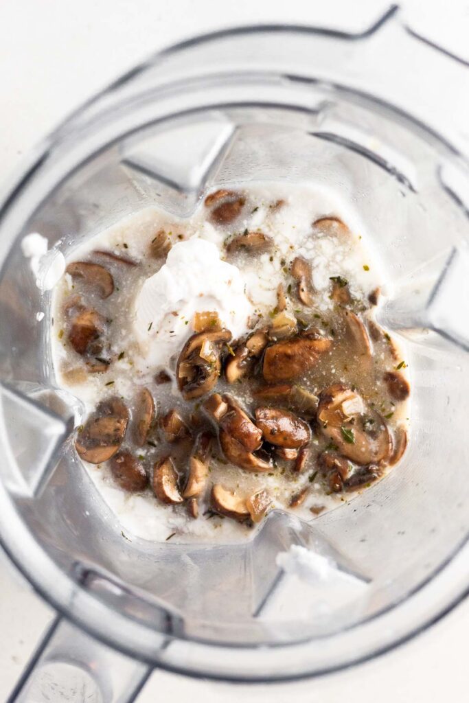 Blender filled with coconut milk and sautéed mushrooms.