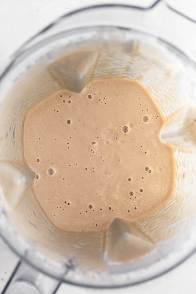 Blender filled with a creamy brown broth.