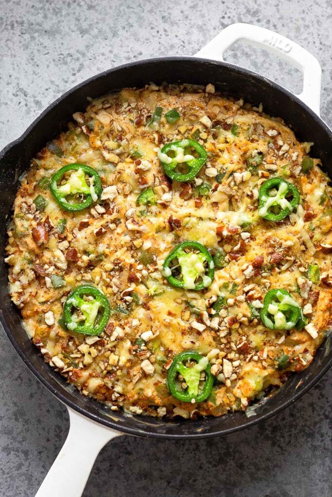 Healthy super bowl recipe of chicken jalapeño casserole topped with crushed pretzels, cheese, and jalapeños.
