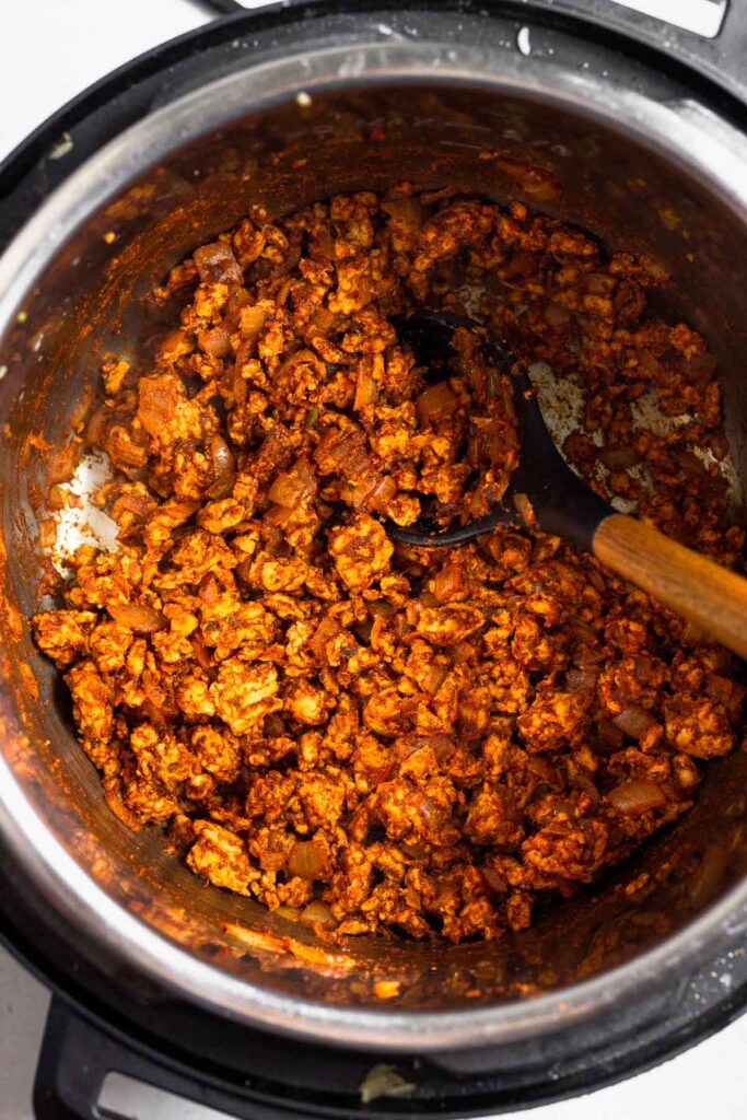 Instant pot filled with seasoned ground turkey.