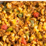 Close up of cheesy taco pasta with ground beef and veggies in a skillet.
