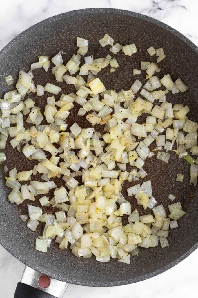 Overhead shot of a skillet filled with sautéed diced onions.