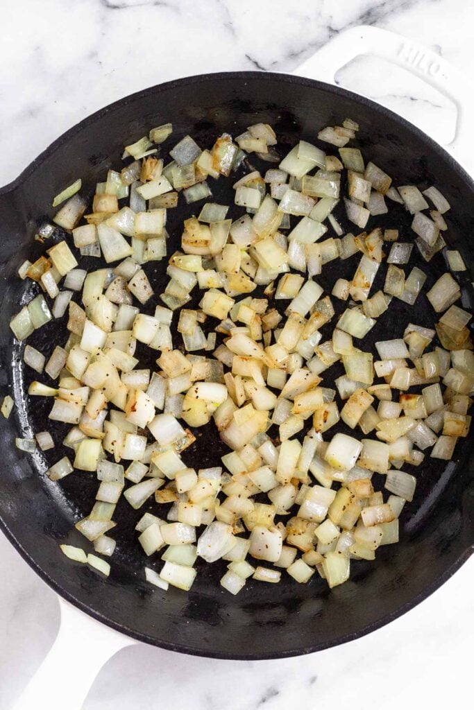 Large cast iron skillet with sautéed diced onions.