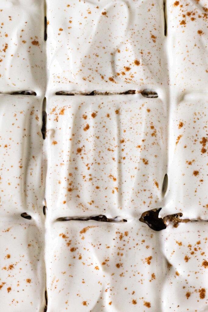 Close up overhead shot of cut iced cake sprinkled with cinnamon.