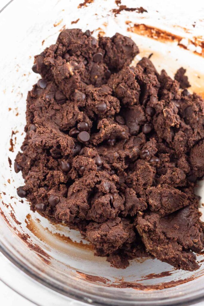 Chocolate batter with chocolate chips in it in a large glass bowl.