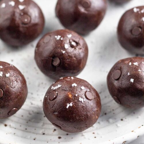 Chocolate protein balls on a white plate. They are sprinkled with sea salt