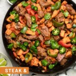 Steak and sweet potato skillet in a large pan topped with jalapeños and cilantro. Around it is a towel, lime wedges, and cilantro.