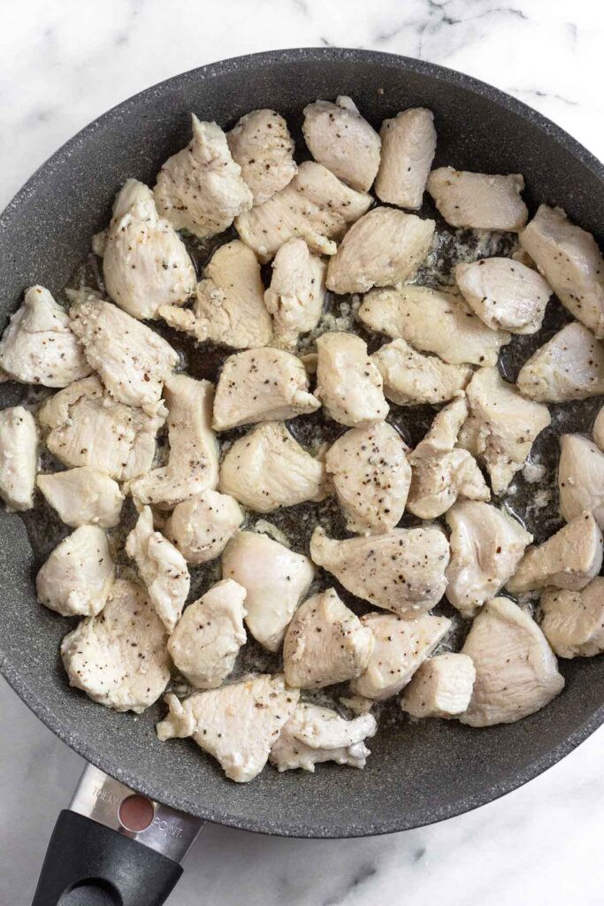 Saute pan filled with cubed cooked chicken breast.