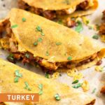 Close up of 3 turkey baked tacos on a baking sheet. They are garnished with cilantro.