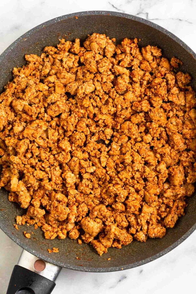 Large skillet filled with seasoned ground turkey in it.