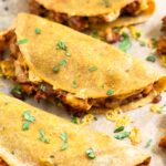 Close up of 3 turkey baked tacos on a baking sheet. They are garnished with cilantro.