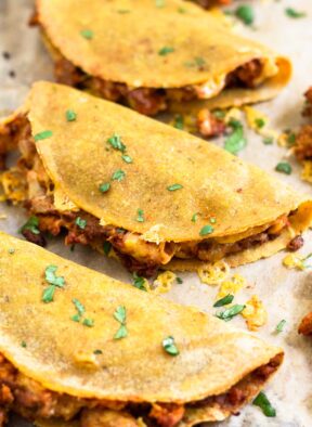 Close up of 3 turkey baked tacos on a baking sheet. They are garnished with cilantro.