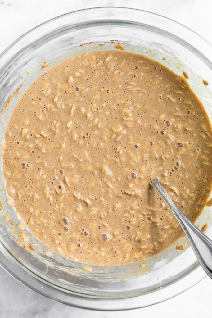 Oats mixed with liquid and spices in a large bowl.