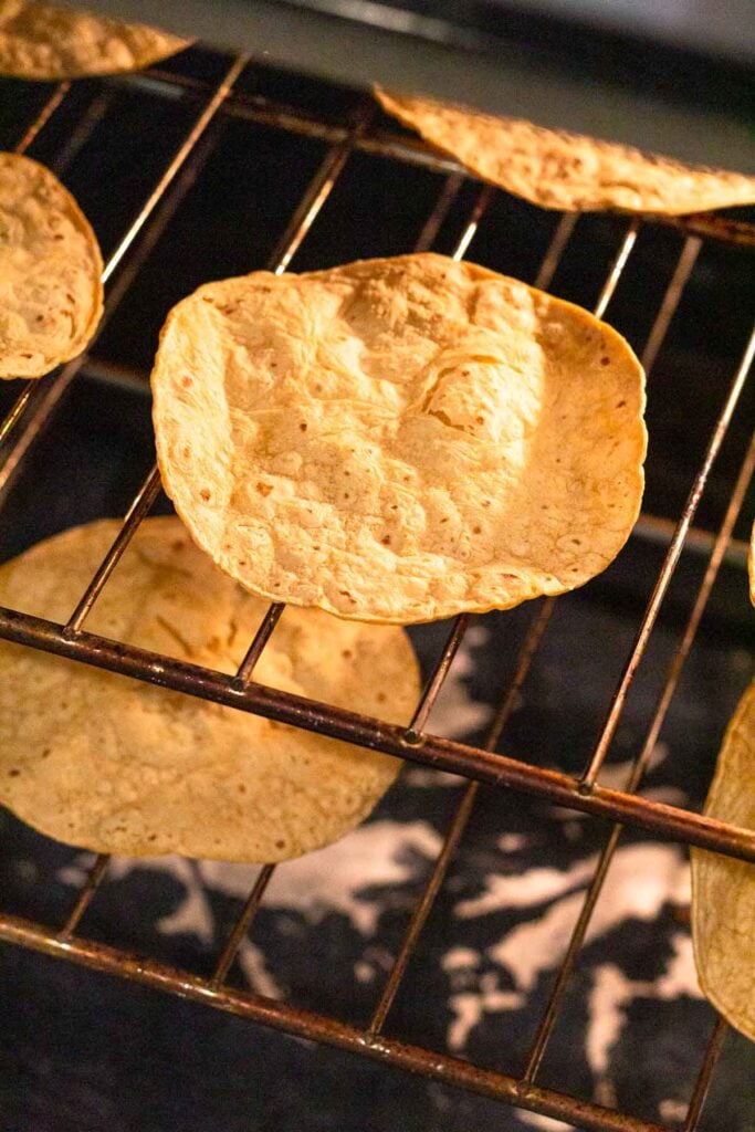 Corn tortillas on the racks in the oven baking until crispy.