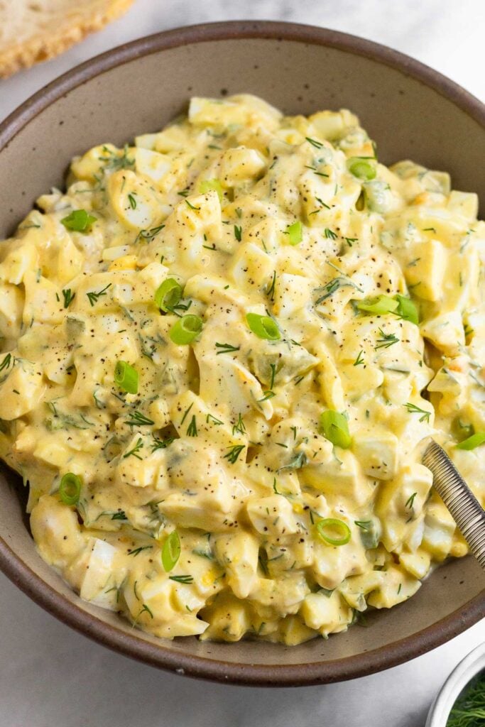 Healthier egg salad recipe in a large bowl with a spoon in it.