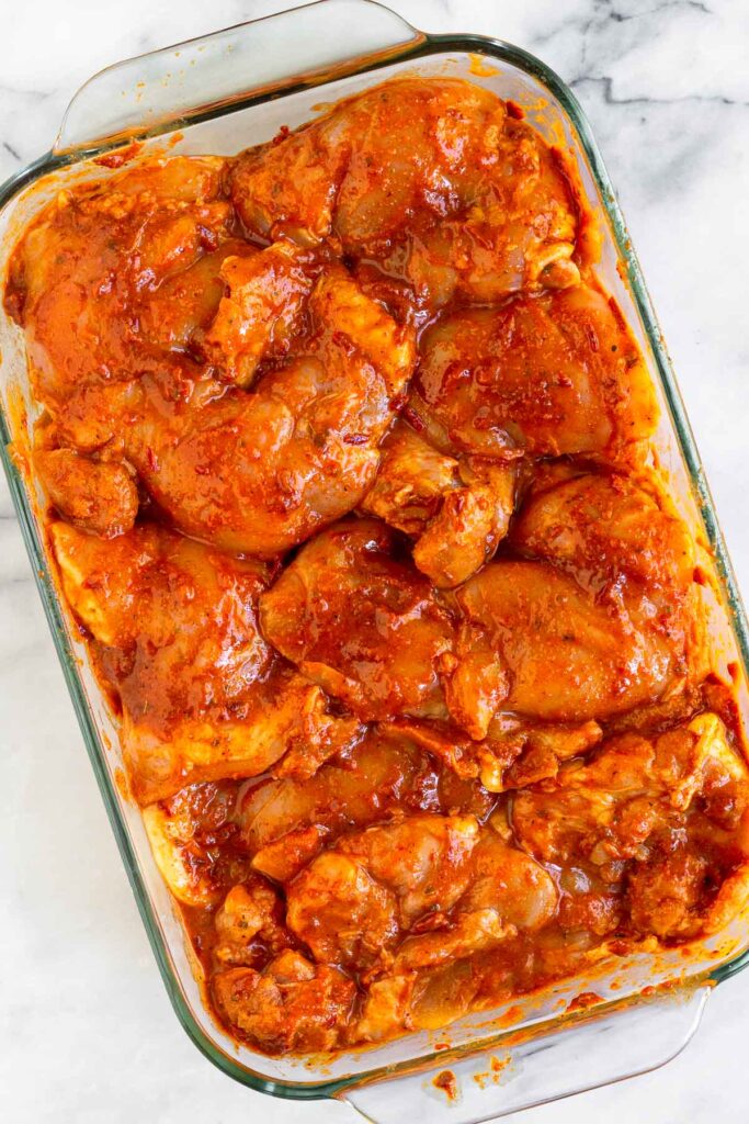 Overhead shot of raw chicken thighs in a baking dish marinating in a honey chipotle marinade.