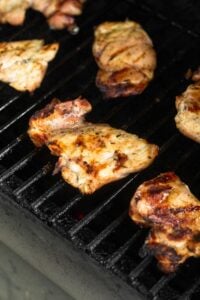 Grilled chicken thighs on a grill.