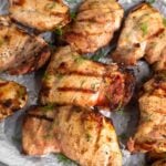 Grilled chicken that was marinated in pickle juice on a baking sheet. They are garnished with fresh dill.