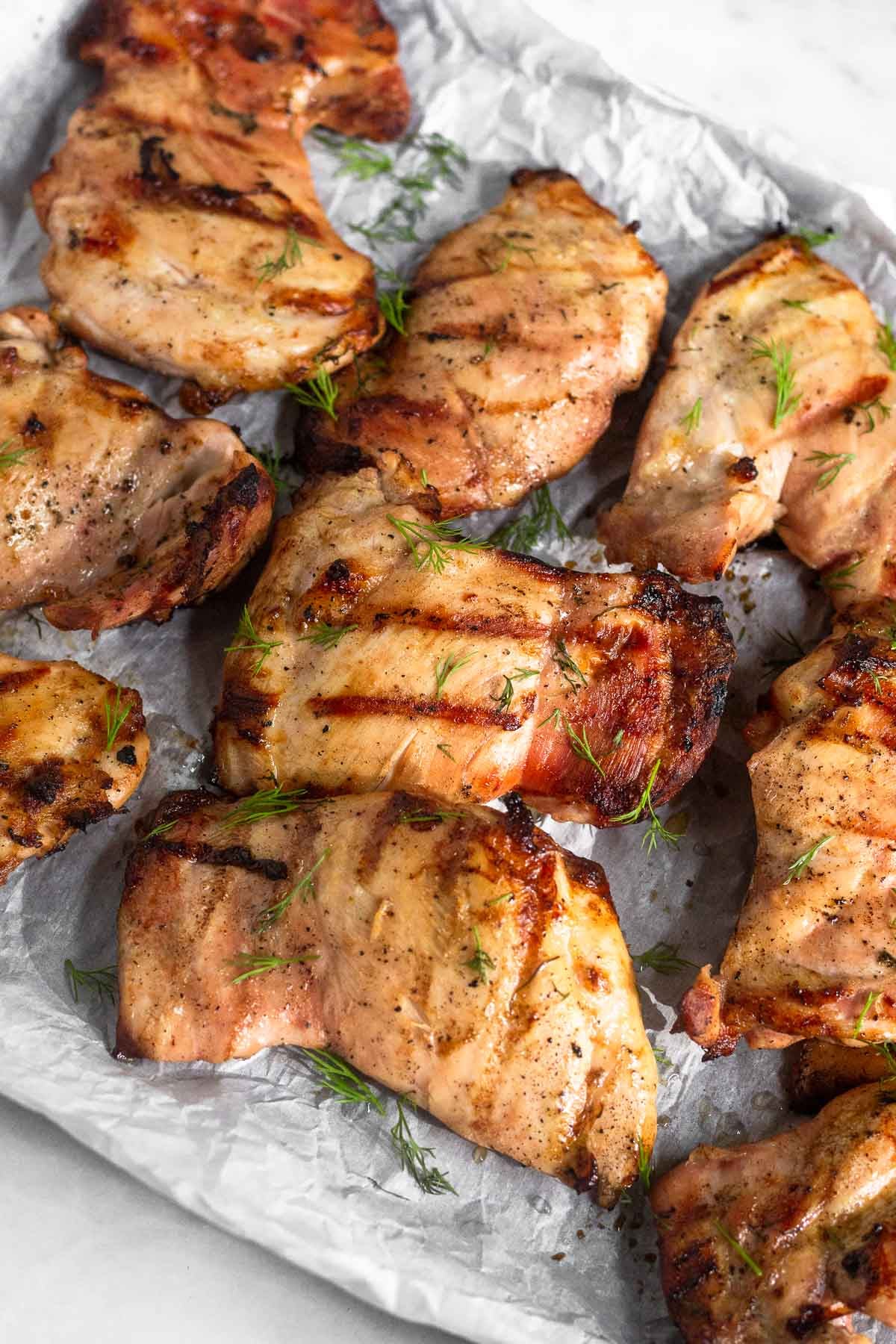Grilled chicken that was marinated in pickle juice on a baking sheet. They are garnished with fresh dill.