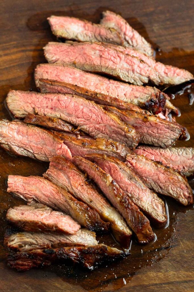 Overhead shot of medium rare pieces of steak that have just been cut on a cutting board.
