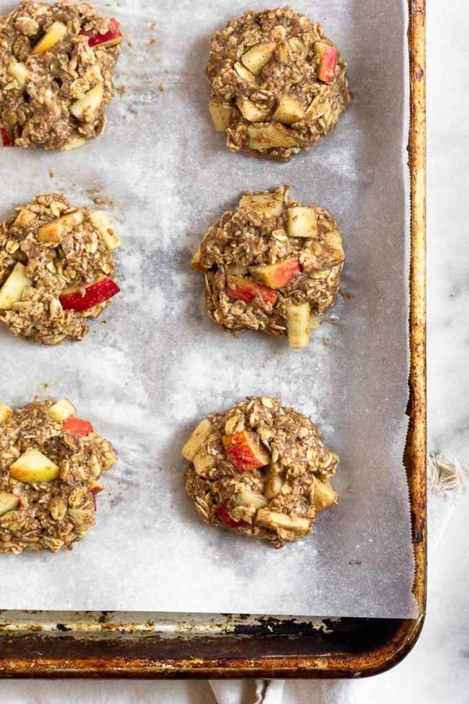 Overhead shot of apple cinnamon oatmeal protein cookies on a baking sheet before they are baked.