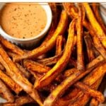 Air fryer sweet potato fries on a plate with a ramekin of dipping sauce.
