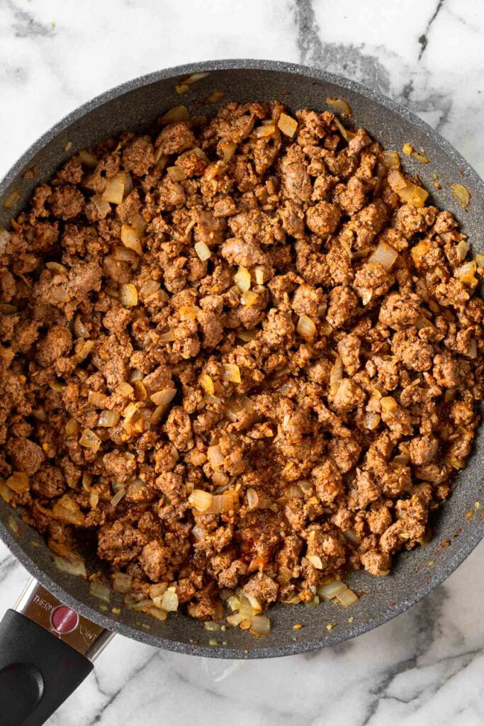 Large skillet filled with seasoned ground beef in it.