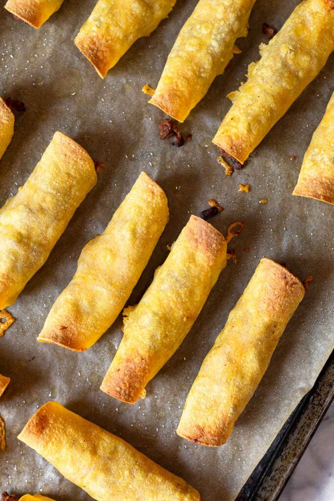A baking sheet of baked beef taquitos.