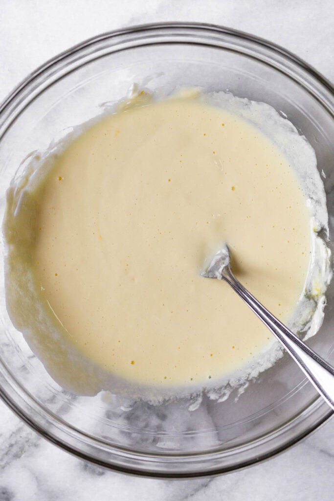 Glass bowl with a wet batter and a fork in it.