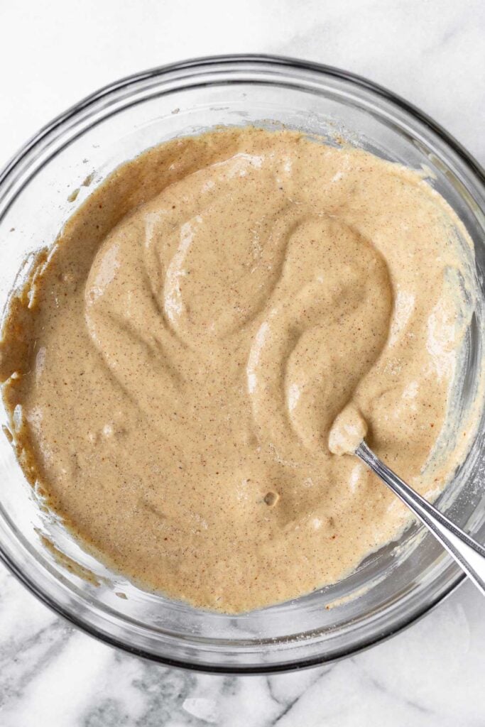 Pancake batter in a glass bowl with a fork in it.