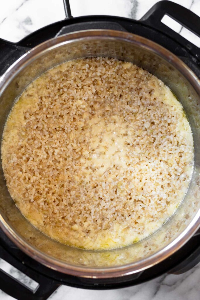 Overhead shot of an instant pot cooked brown rice with pockets of melted cheese in it.
