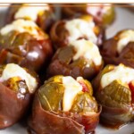 Prosciutto wrapped figs stuffed with goat cheese and drizzled with honey on a white plate.