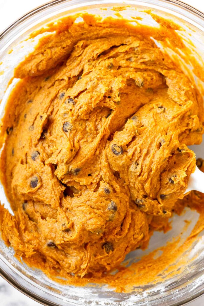 Cake-like batter with chocolate chips in it in a large glass bowl with a fork in it.