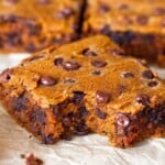 Close up of a pumpkin chocolate chip bar with a bite taken out of it. Behind it are more bars lined up.
