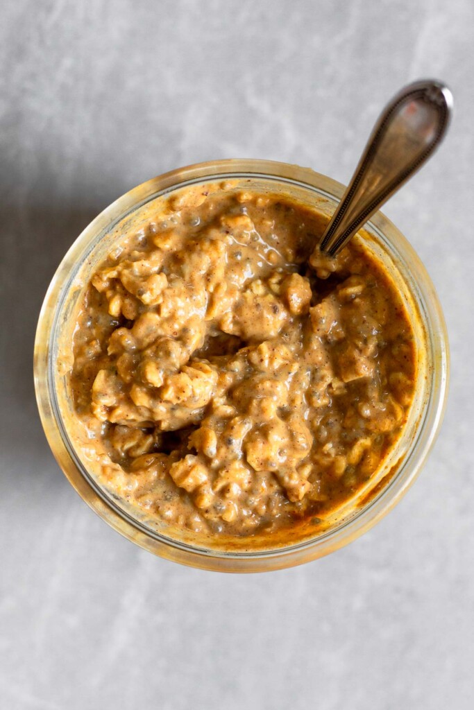 Overhead shot of protein pumpkin overnight oats in a jar with in a spoon in the jar.