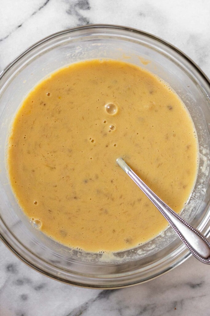 Glass bowl with a wet batter and a fork in it.