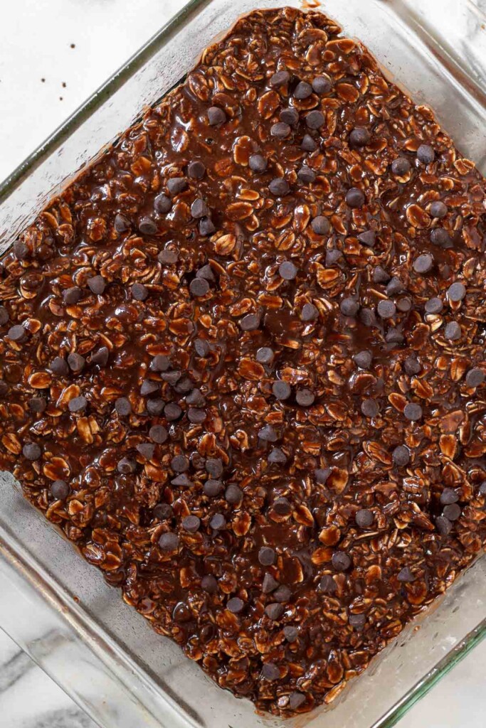 Overhead shot of a pan of chocolate oatmeal sprinkled with chocolate chips before it is baked.