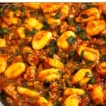 Sausage gnocchi skillet with spinach mixed with pasta sauce in a large pan.