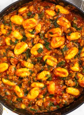 Sausage gnocchi skillet with spinach mixed with pasta sauce in a large pan.