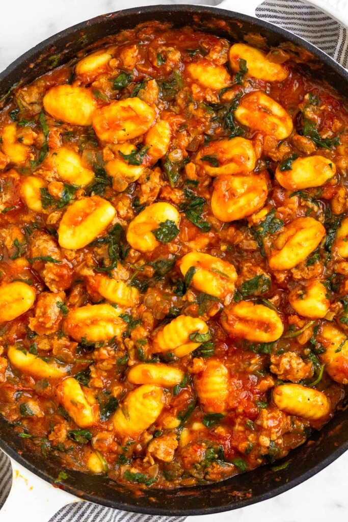 Sausage gnocchi skillet with spinach mixed with pasta sauce in a large pan.