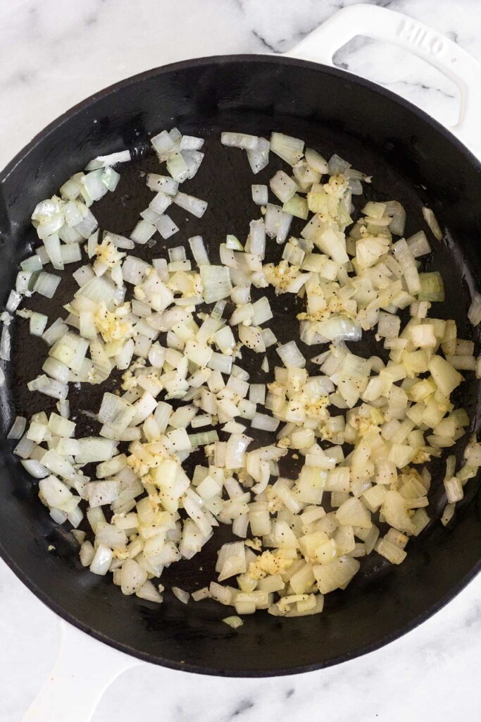 Large skillet filled with sautéed diced onion in it.