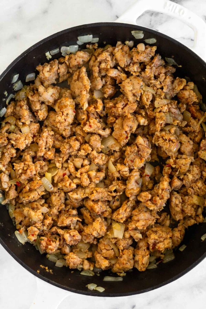 Large skillet filled with cooked ground sausage in it.