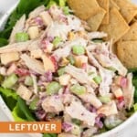 Leftover turkey salad with apples and celery in a bowl with some crackers overtop some greens.