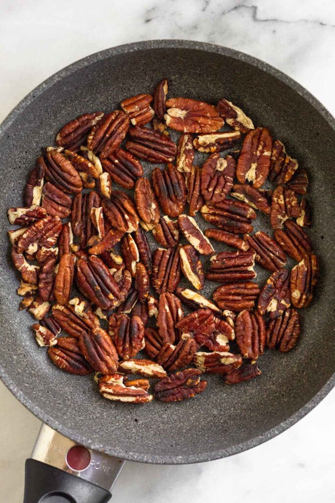 Small skillet filled with toasted pecans.