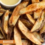 Baked potato wedges piled on a plate with a ramekin of honey mustard.
